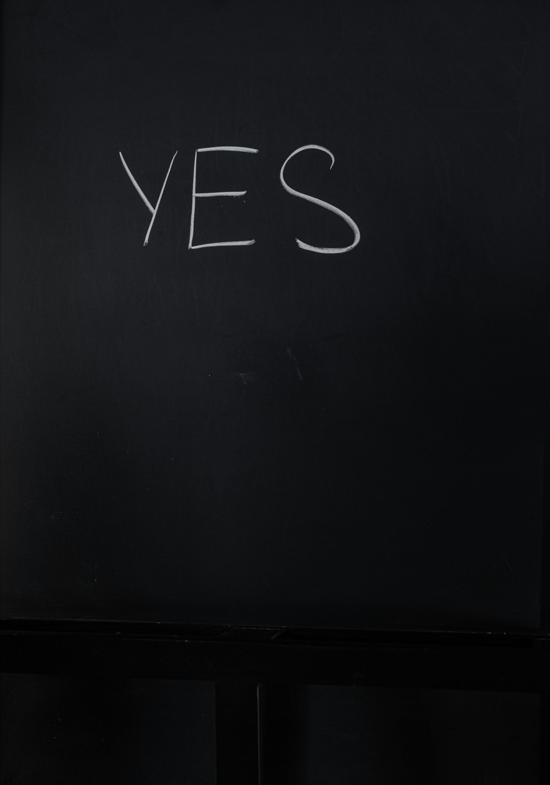 pexels-photo-3825278-3825278-1 A minimalistic chalkboard with 'YES' written in bold white chalk.
